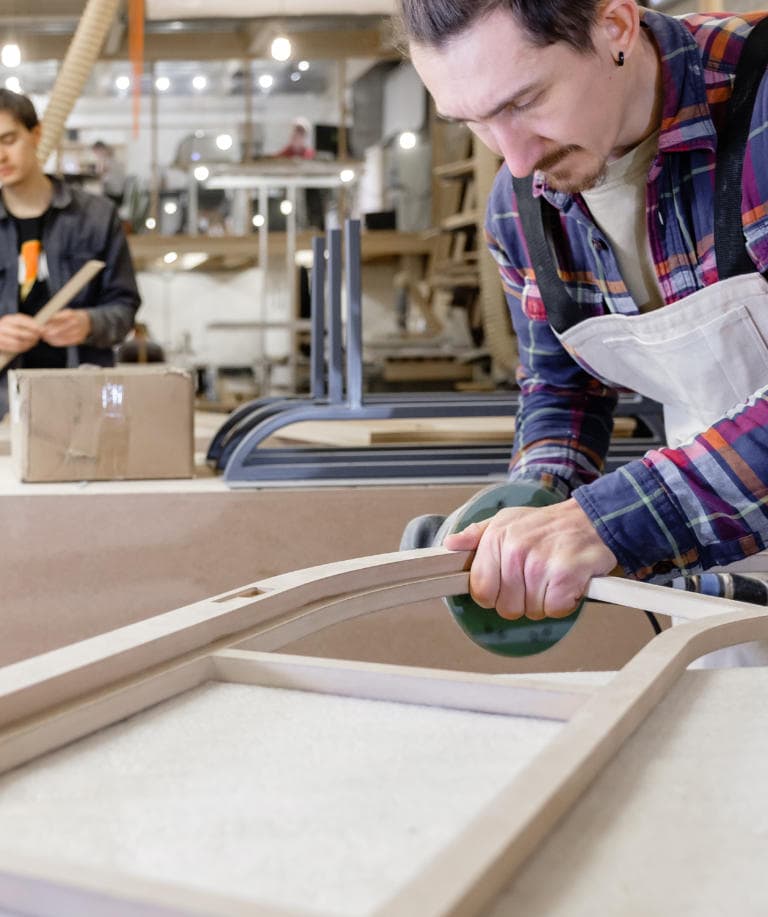 Young serious man hipster master carpenter in shirt on wood industry makes a new product for the next collection. Concept of work in woodworking or furniture production