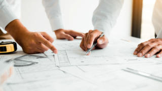 Architects or engineering working with blueprints and discussing