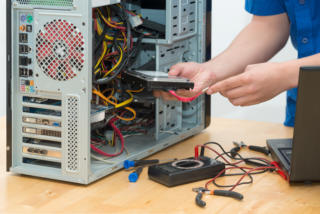 Young technician working on broken computer in his office