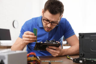Male technician repairing computer at table indoors