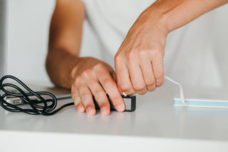 Man's hands connecting powerbank to a laptop through usb-hub